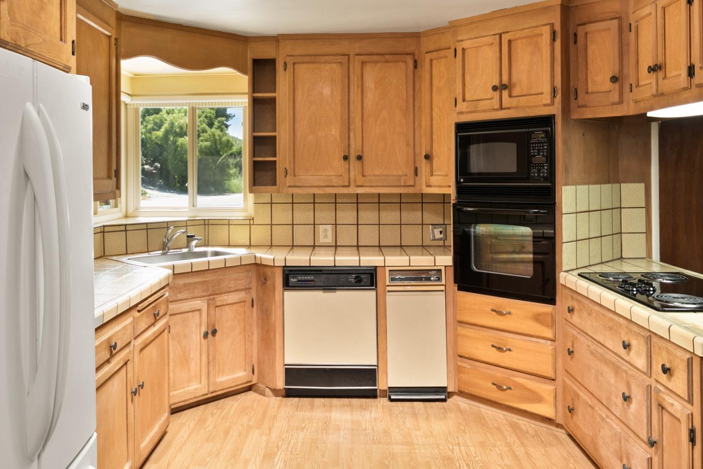 3240 Rio Road Carmel, CA 93923 - Photo 8 of 37 a kitchen with granite countertop white cabinets and window