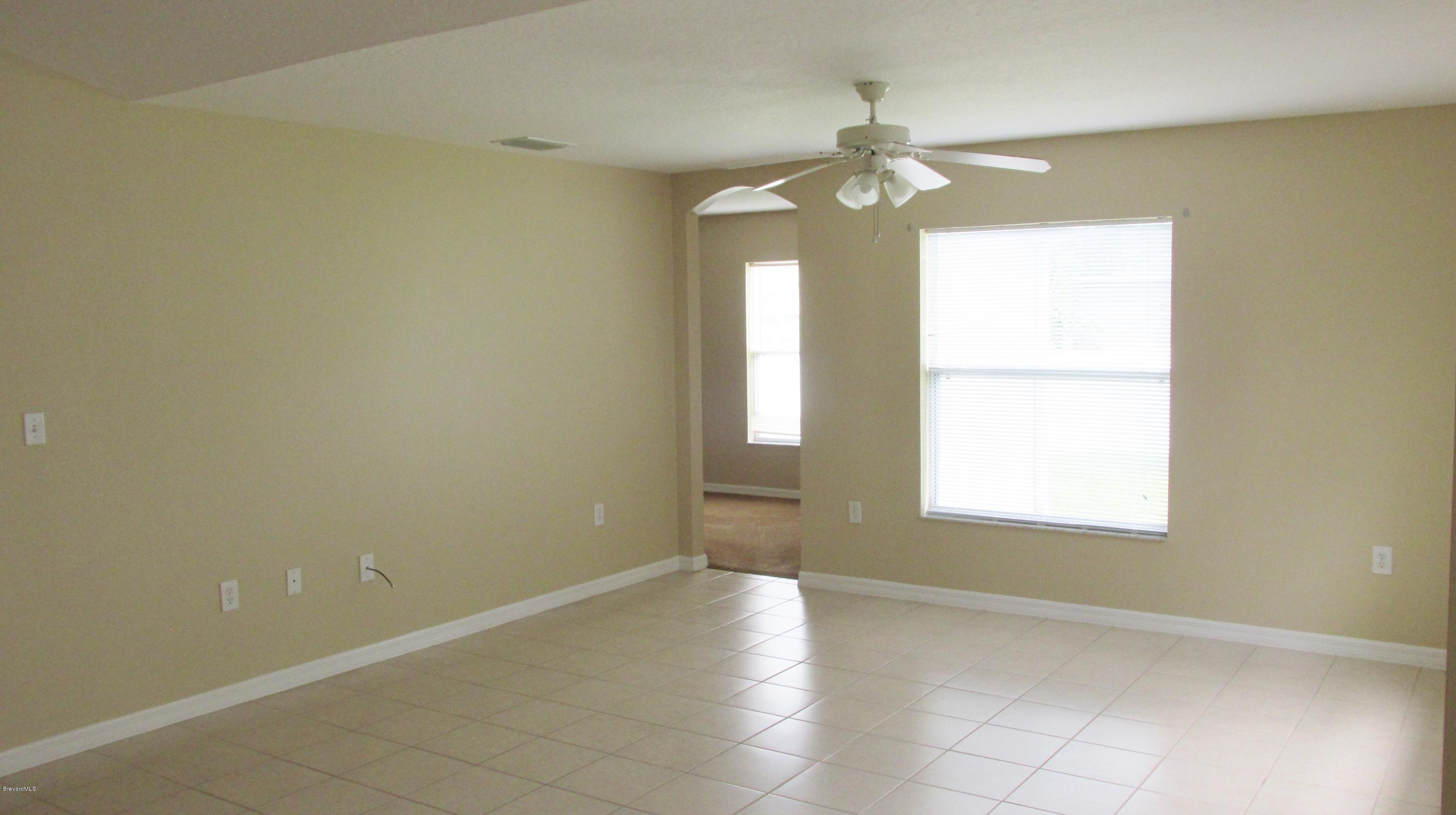 174 Tudor Road Southwest Palm Bay, FL 32908 - Photo 19 of 20 an empty room with chandelier fan and windows