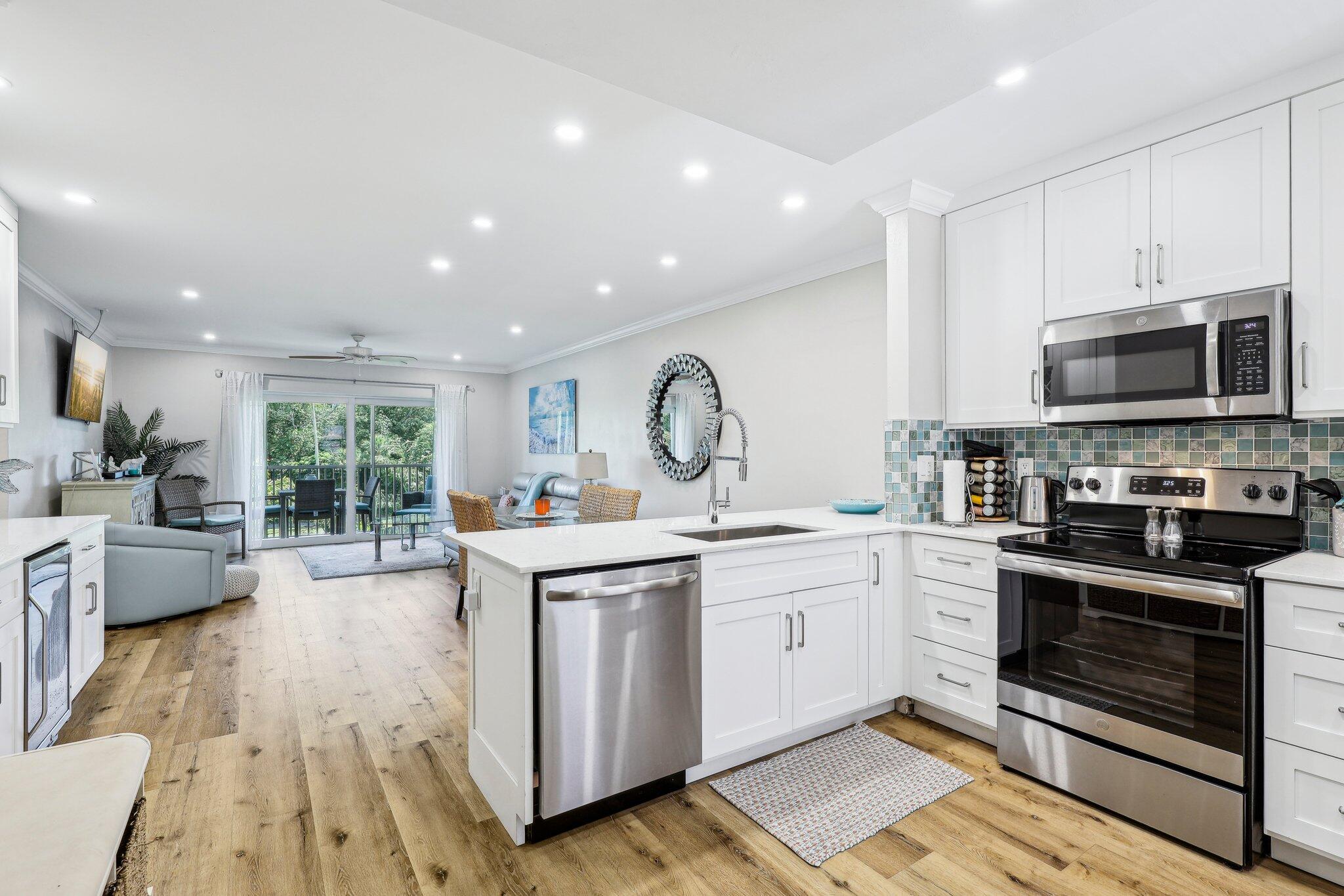 200 East Royal Palm Road, Unit 304 Boca Raton, FL 33432 - Photo 10 of 37 a open kitchen with stainless steel appliances granite countertop a stove top oven a sink dishwasher and white cabinets with wooden floor