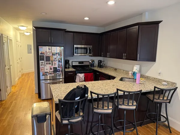 a kitchen with granite countertop a dining table chairs and a refrigerator