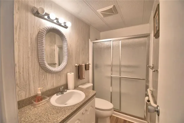 a bathroom with a granite countertop sink toilet mirror and shower