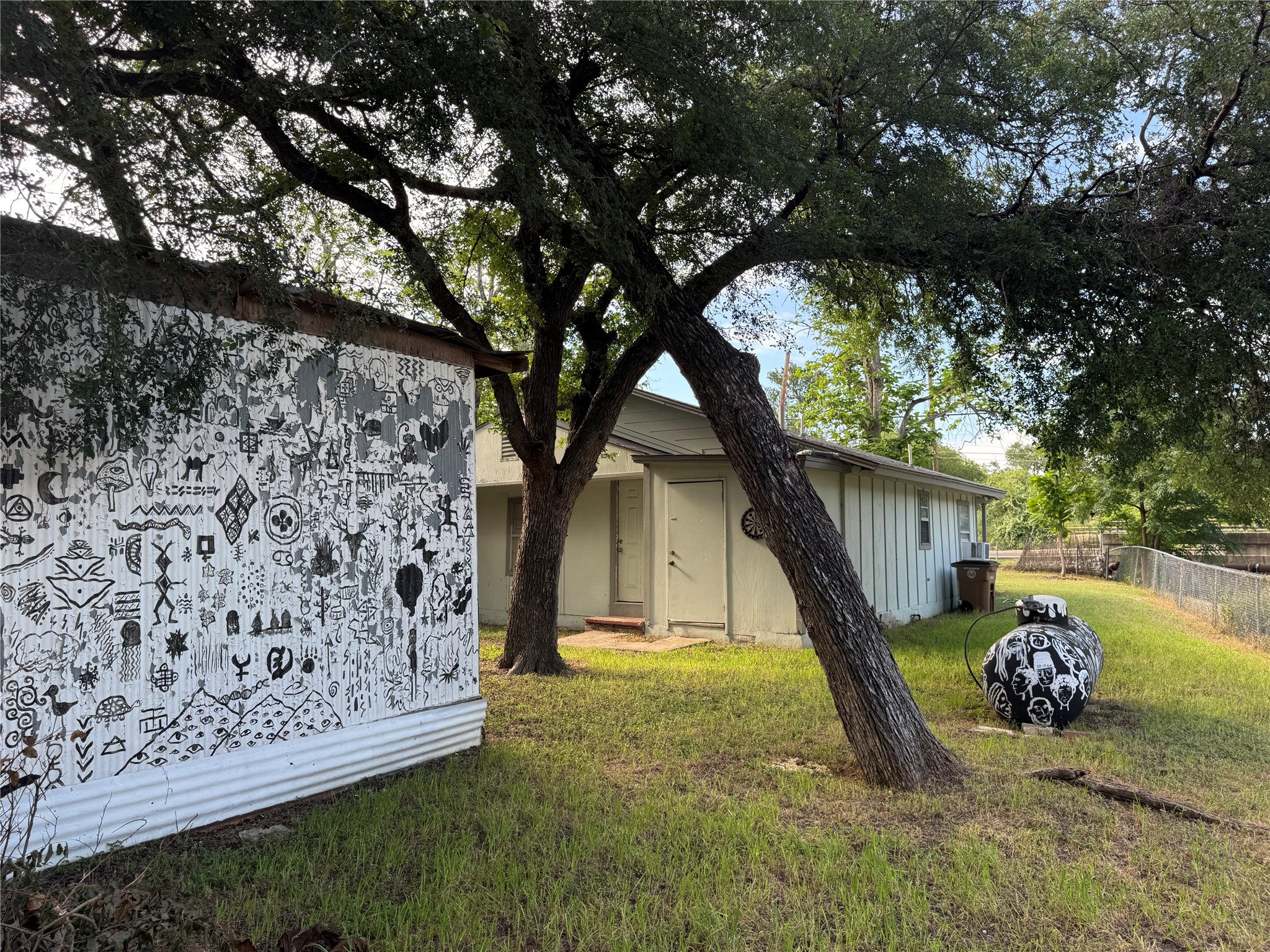 5007 Heflin Lane Austin, TX 78721 - Photo 21 of 25 Mature trees shade this property, offering natural canopy over a fenced yard with a shed.
