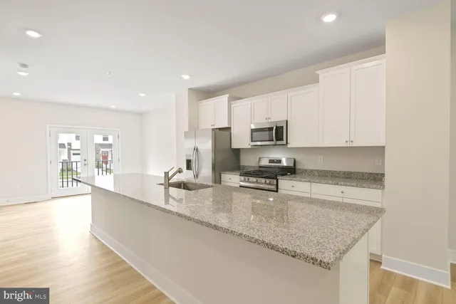 a large kitchen with granite countertop a sink a counter top space appliances and cabinets