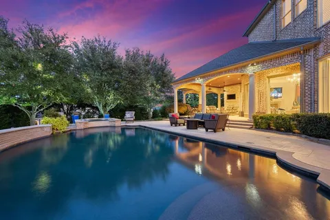 a view of swimming pool with outdoor seating and trees in the background