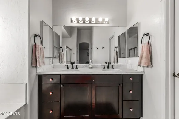 a bathroom with double vanity sinks a vanity and a large mirror