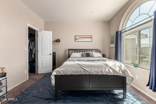 a bedroom with a bed table and a large window