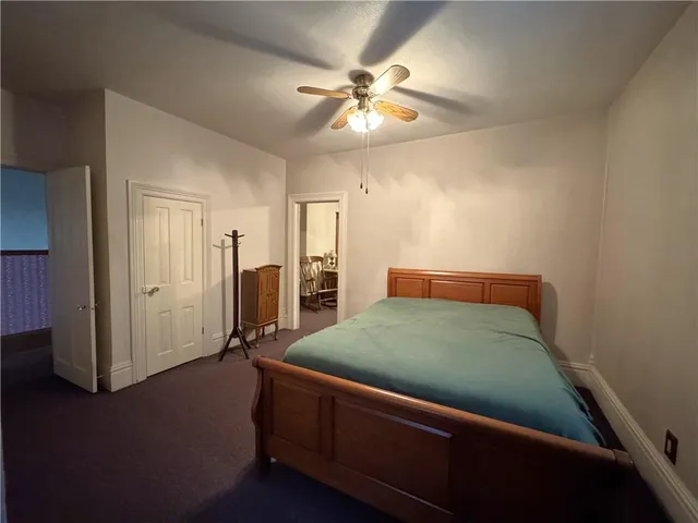 a room with a bed and ceiling fan