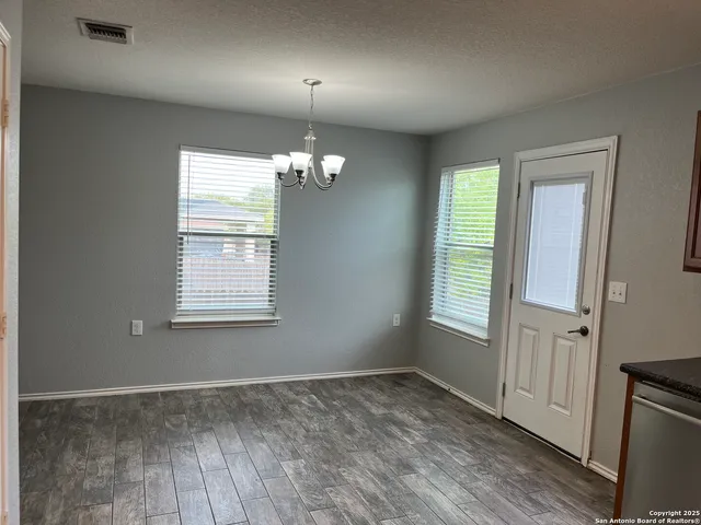 an empty room with wooden floor closet and windows