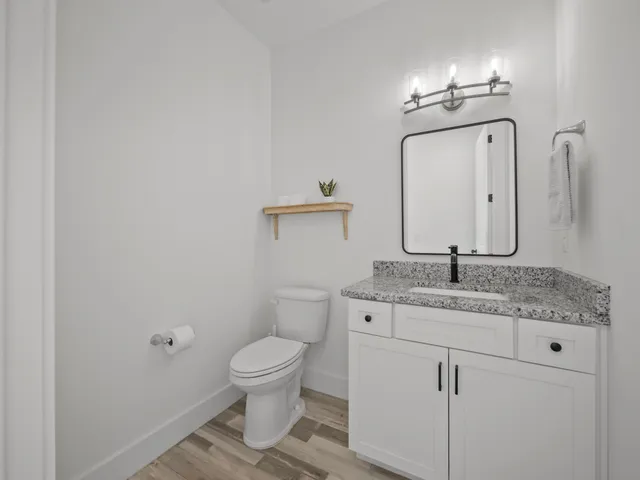 a bathroom with a granite countertop toilet a sink and mirror