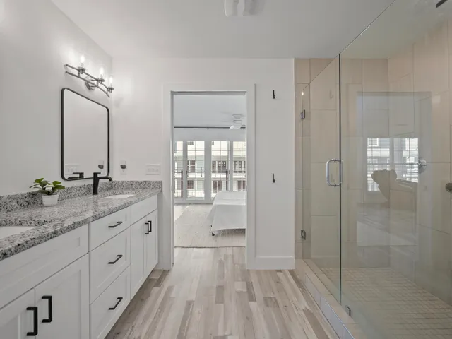 a bathroom with a granite countertop sink a mirror a glass door and shower