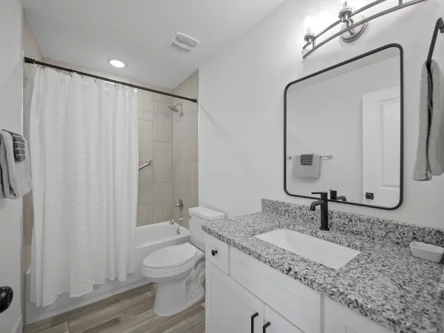 a bathroom with a granite countertop sink a toilet and a mirror