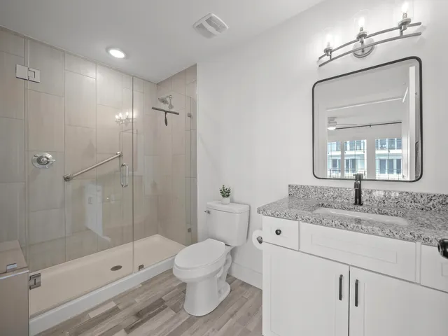 a bathroom with a granite countertop sink toilet and shower
