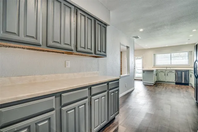 a kitchen with stainless steel appliances granite countertop a refrigerator a sink dishwasher and white cabinets with wooden floor