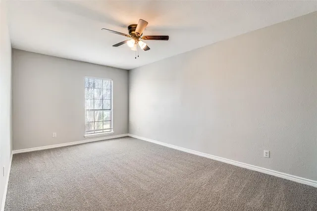 an empty room with windows and chandelier fan