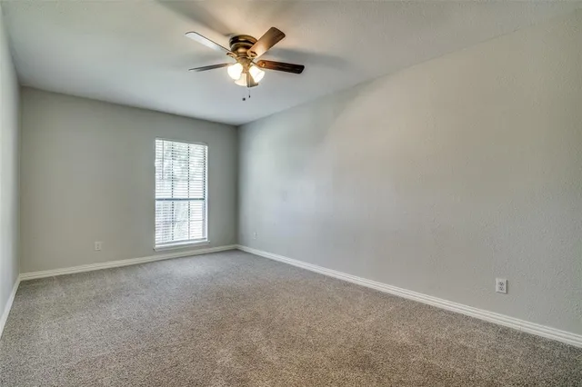 an empty room with windows and chandelier fan