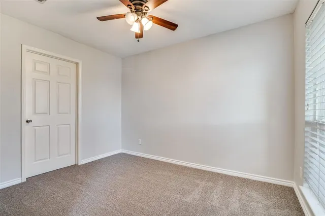an empty room with a window and a fan