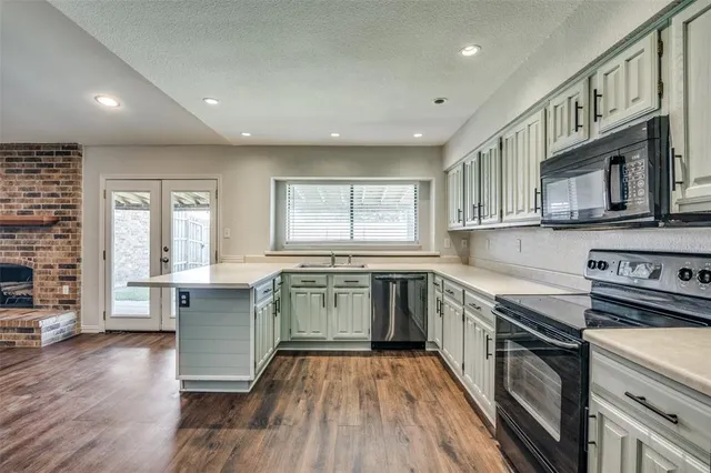 a kitchen with stainless steel appliances granite countertop hardwood floor sink stove dining table and chairs