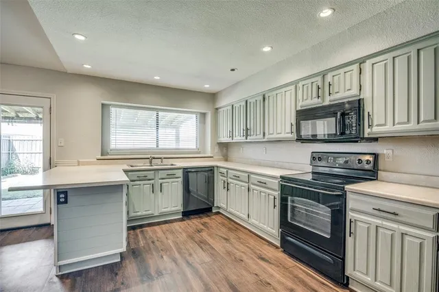 a kitchen with a sink stove oven and wooden floor