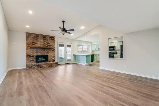 an empty room with wooden floor fireplace and a window