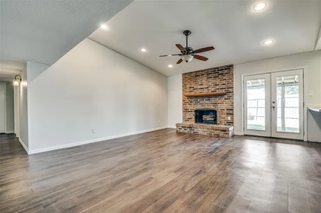 an empty room with wooden floor fireplace and windows