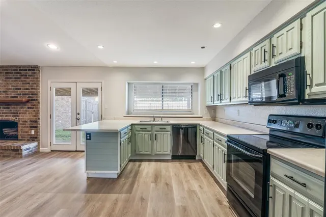 a kitchen with stainless steel appliances granite countertop a stove top oven a sink dishwasher a dining table and chairs with wooden floor