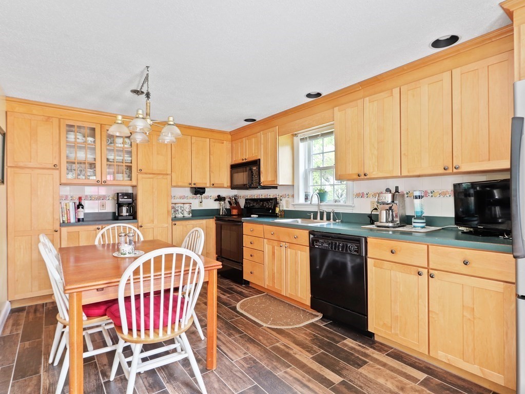 26 Elda Road Framingham, MA 01701 - Photo 5 of 27 a kitchen with stainless steel appliances granite countertop a stove a sink dishwasher a dining table and chairs with wooden floor