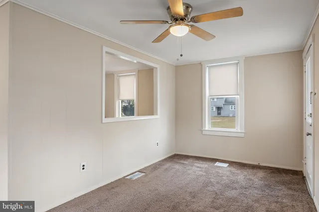 an empty room with windows and fan
