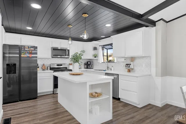 a kitchen with kitchen island a sink stainless steel appliances and white cabinets