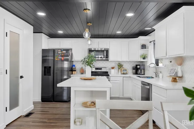 a kitchen with stainless steel appliances granite countertop a sink refrigerator and cabinets