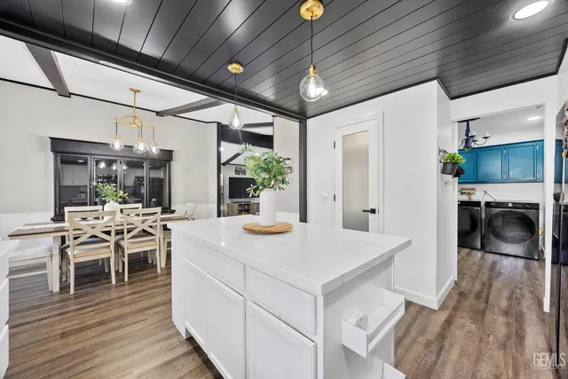 a kitchen with stainless steel appliances kitchen island granite countertop a table chairs and a refrigerator