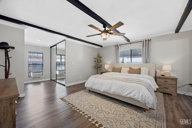 a spacious bedroom with a bed a dresser and wooden floor