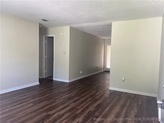 a view of an empty room with wooden floor and closet