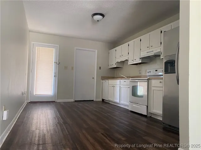 a kitchen with cabinets wooden floor and stainless steel appliances