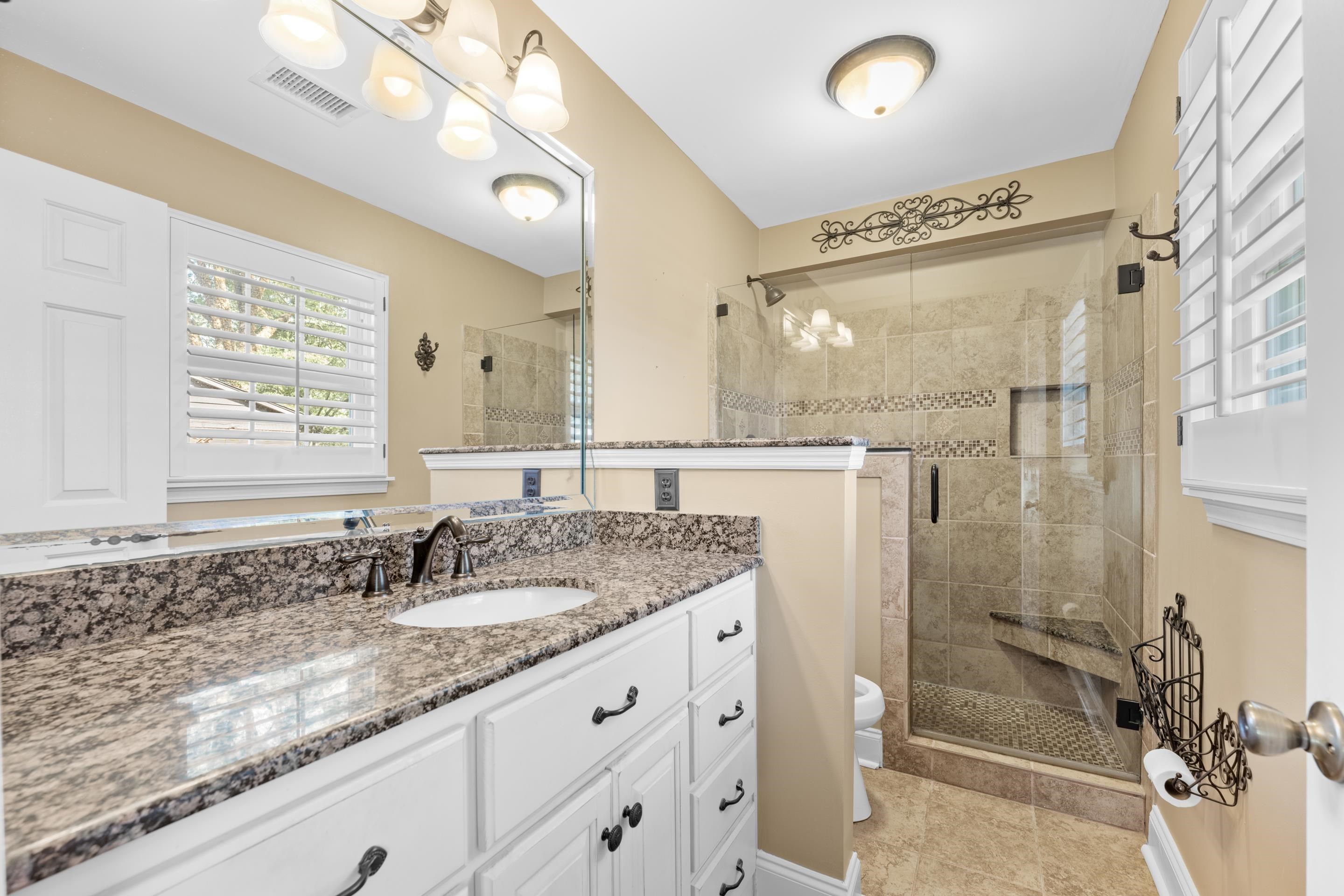 1751 Magnolia Tree Road Germantown, TN 38138 - Photo 27 of 36 a bathroom with a granite countertop sink a mirror and a shower
