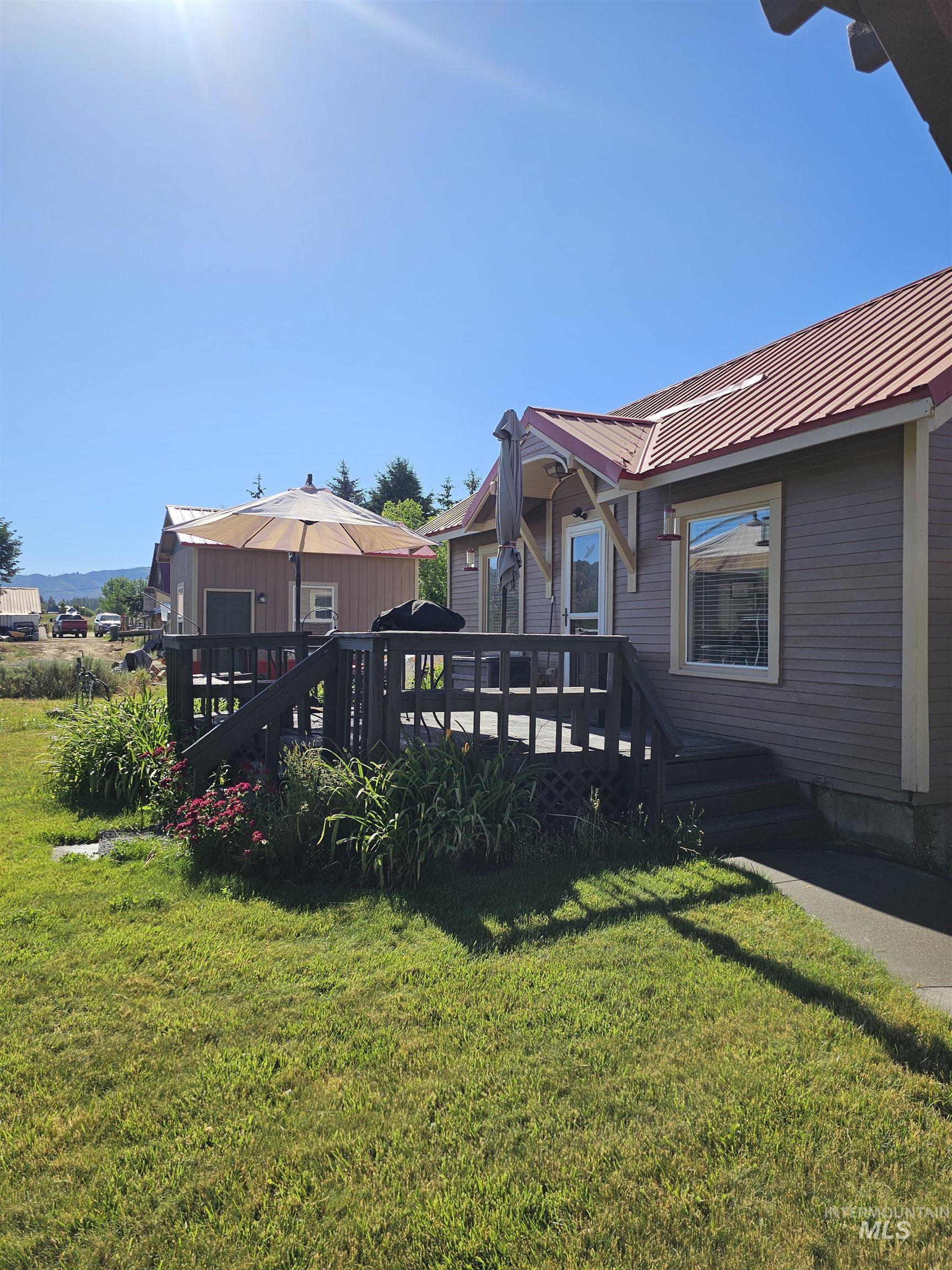 100 Prairie Road Mountain Home, ID 83647 - Photo 5 of 32 Exterior featuring a red metal roof, gray siding, a wood deck with railings, and a side entrance