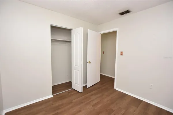 a view of an empty room with wooden floor and closet