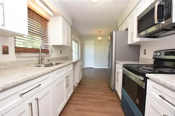 a kitchen with stainless steel appliances granite countertop a sink a stove and a wooden floors