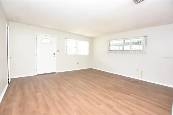 an empty room with wooden floor and windows