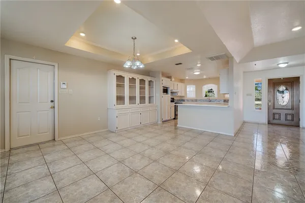 a view of an empty room with kitchen and window
