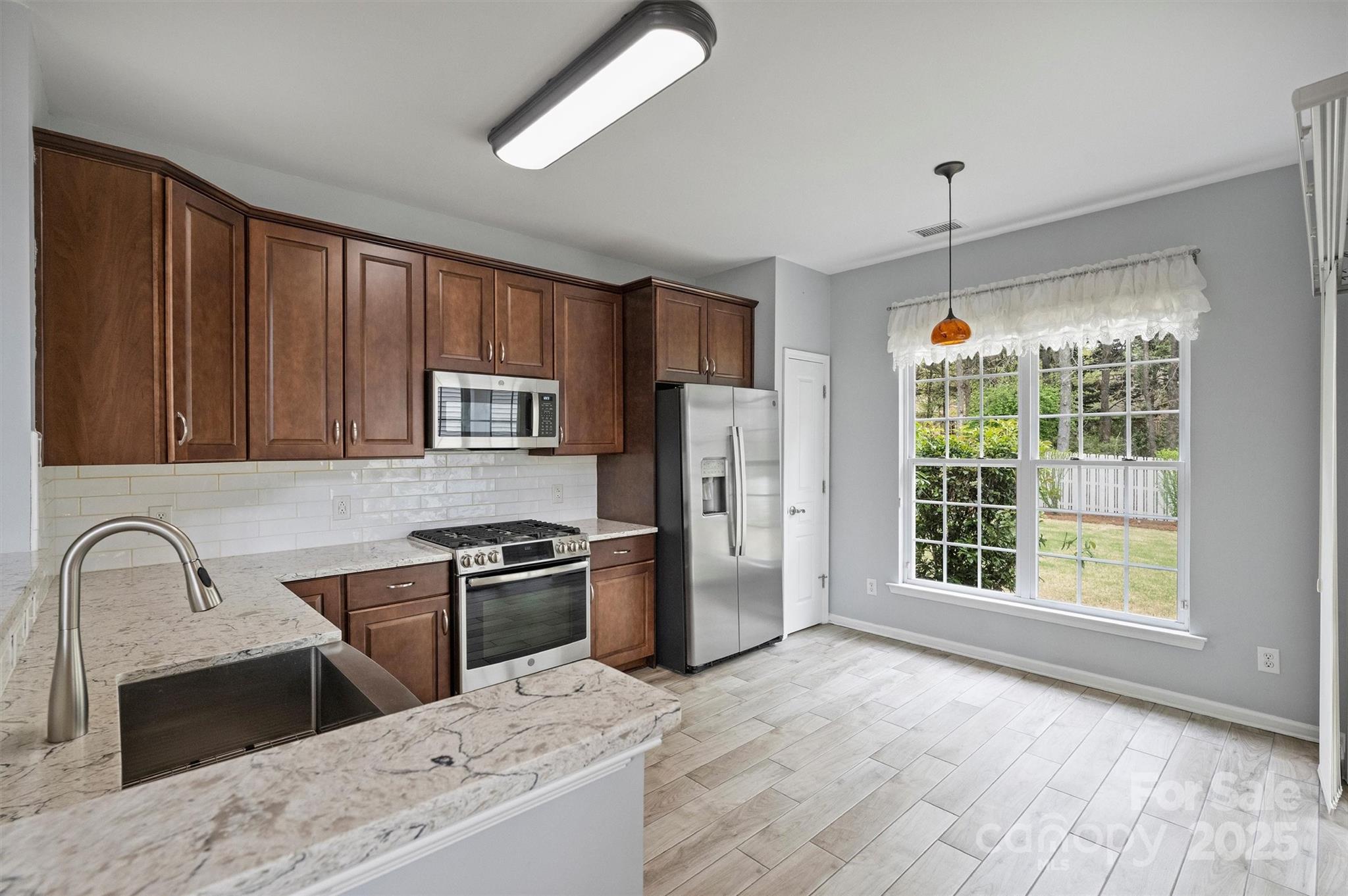 11422 Nevermore Way Charlotte, NC 28277 - Photo 10 of 34 a kitchen with stainless steel appliances granite countertop a stove a sink dishwasher a refrigerator and wooden cabinets with wooden floor