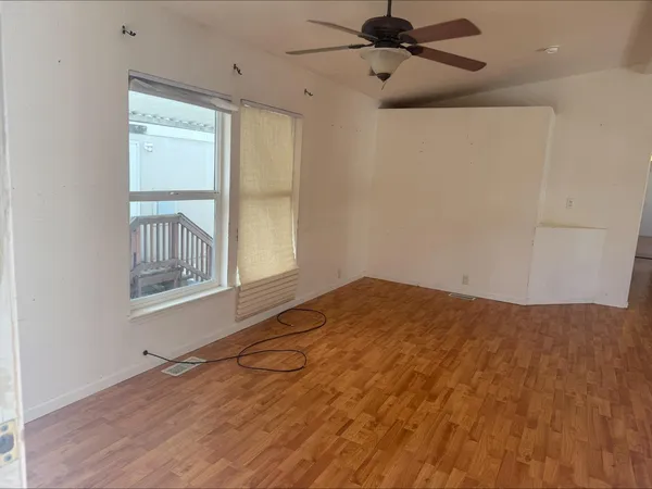 a view of empty room with wooden floor and fan