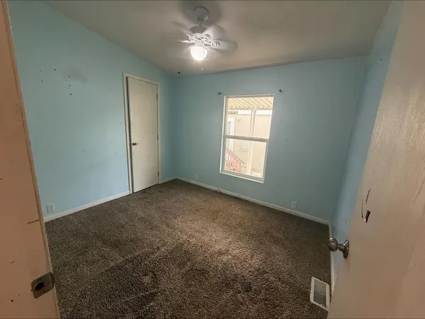 an empty room with windows and fan