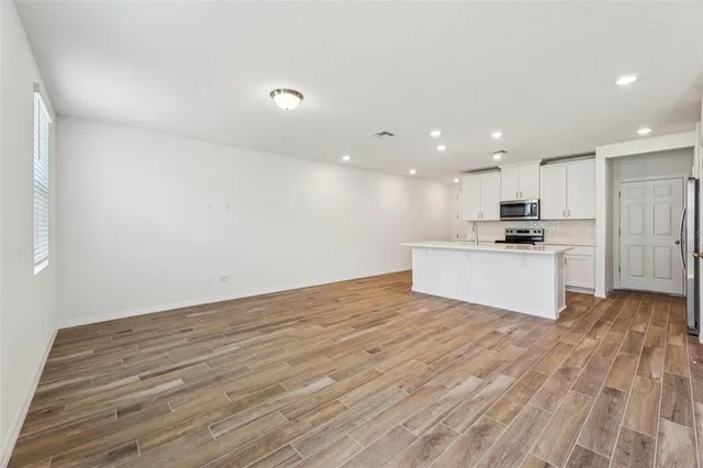 a view of kitchen with wooden floor and white cabinets