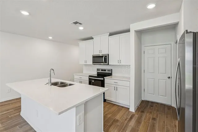 a kitchen that has a microwave a stove and white cabinets with wooden floor