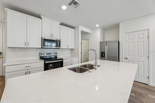 a kitchen with stainless steel appliances a refrigerator sink microwave and cabinets