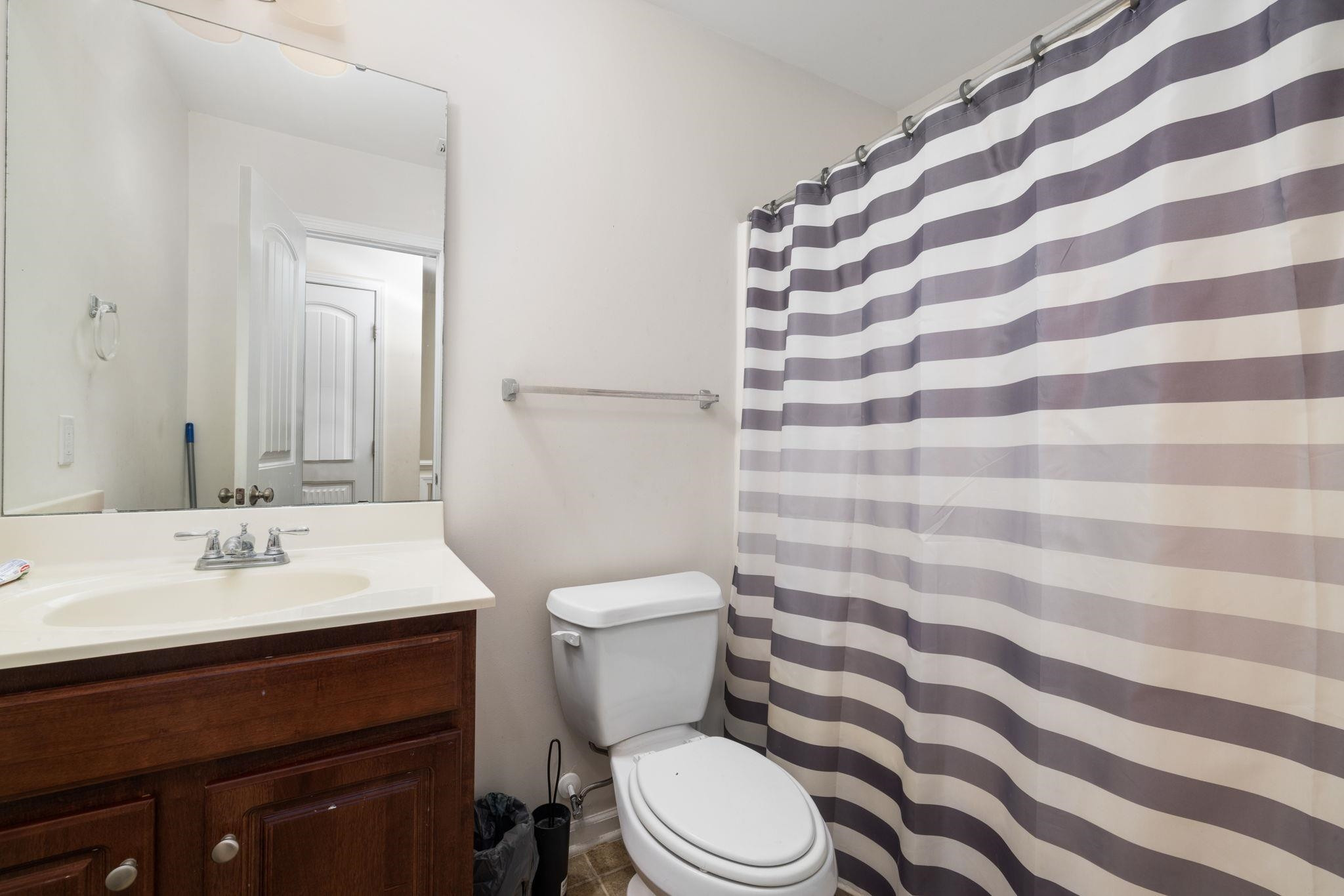 3853 Volkswalk Place Raleigh, NC 27610 - Photo 14 of 19 a bathroom with a sink a toilet a mirror and shower curtain