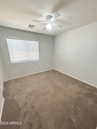 an empty room with a ceiling fan and window