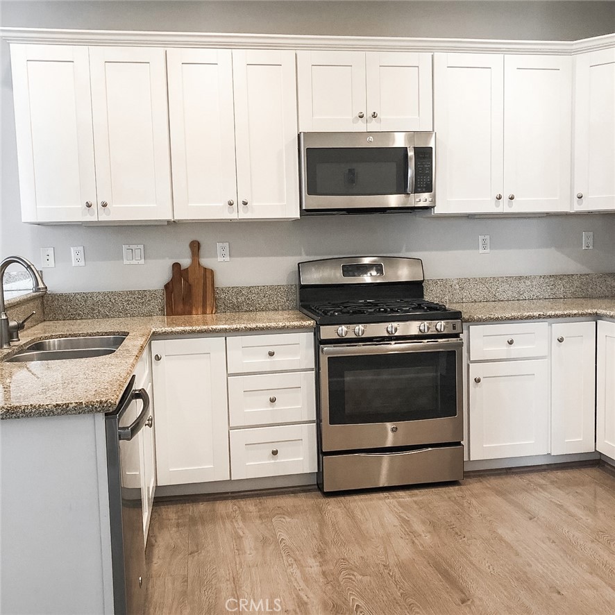 18 Avalon, Unit 5 Irvine, CA 92602 - Photo 3 of 6 a kitchen with granite countertop white cabinets and stainless steel appliances