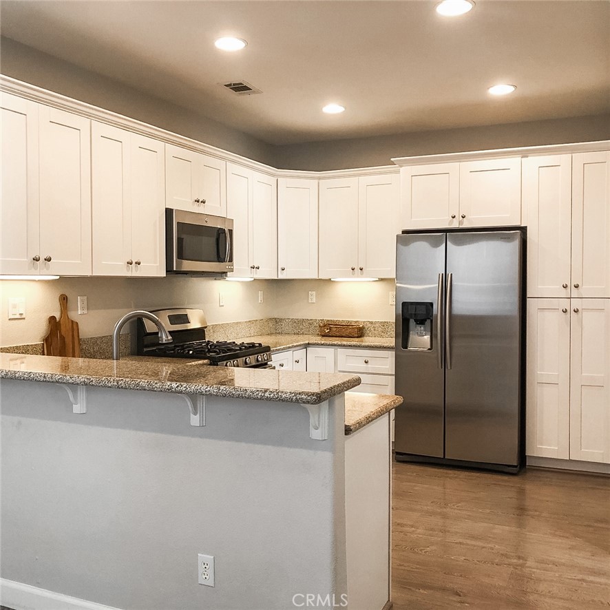 18 Avalon, Unit 5 Irvine, CA 92602 - Photo 4 of 6 a kitchen with stainless steel appliances granite countertop a refrigerator a sink a stove a microwave and white cabinets