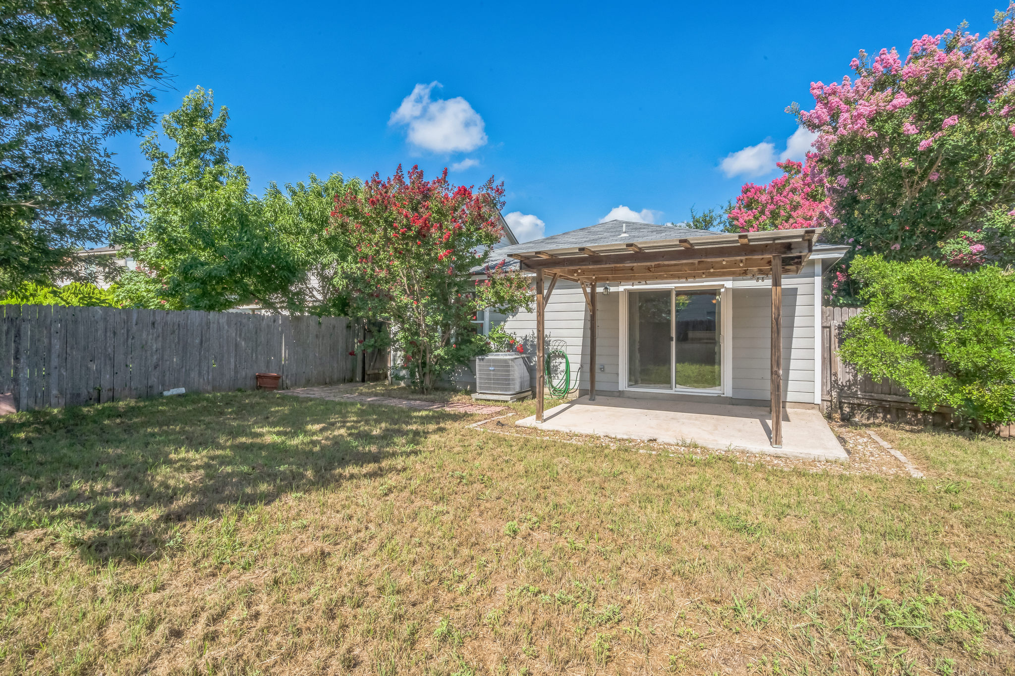 77 Jan Lane Georgetown, TX 78626 - Photo 4 of 16 An inviting backyard oasis awaits with a pergola-covered patio, ideal for outdoor leisure.